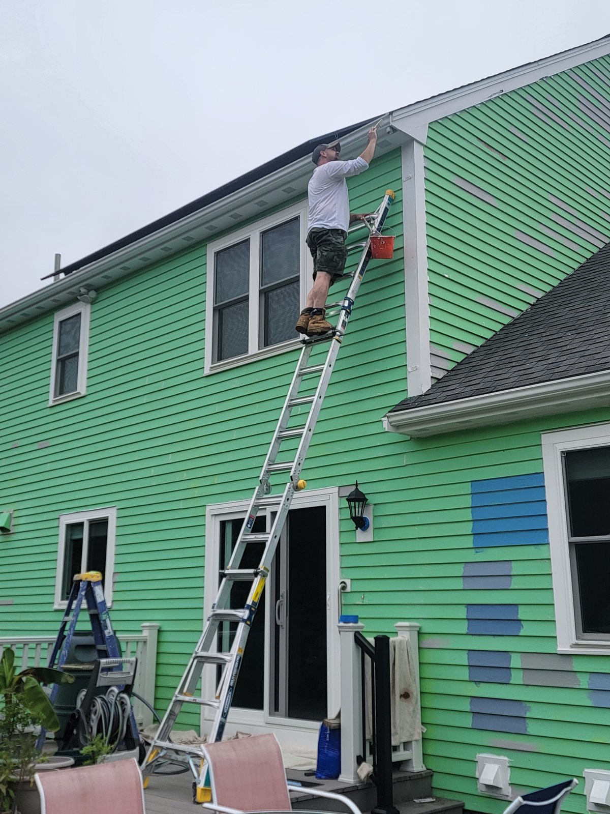 Pia Painting crew member painting exterior trim from a ladder