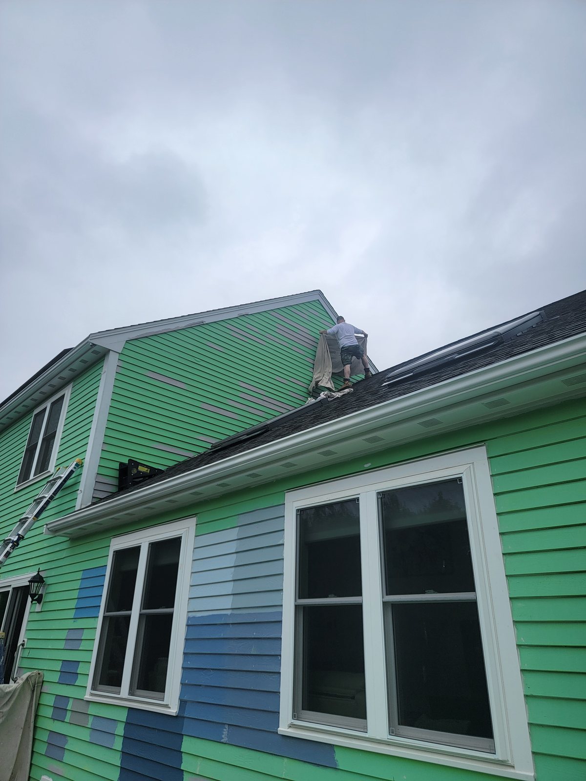 Pia Painting crew member covering a roof section to protect it during exterior painting